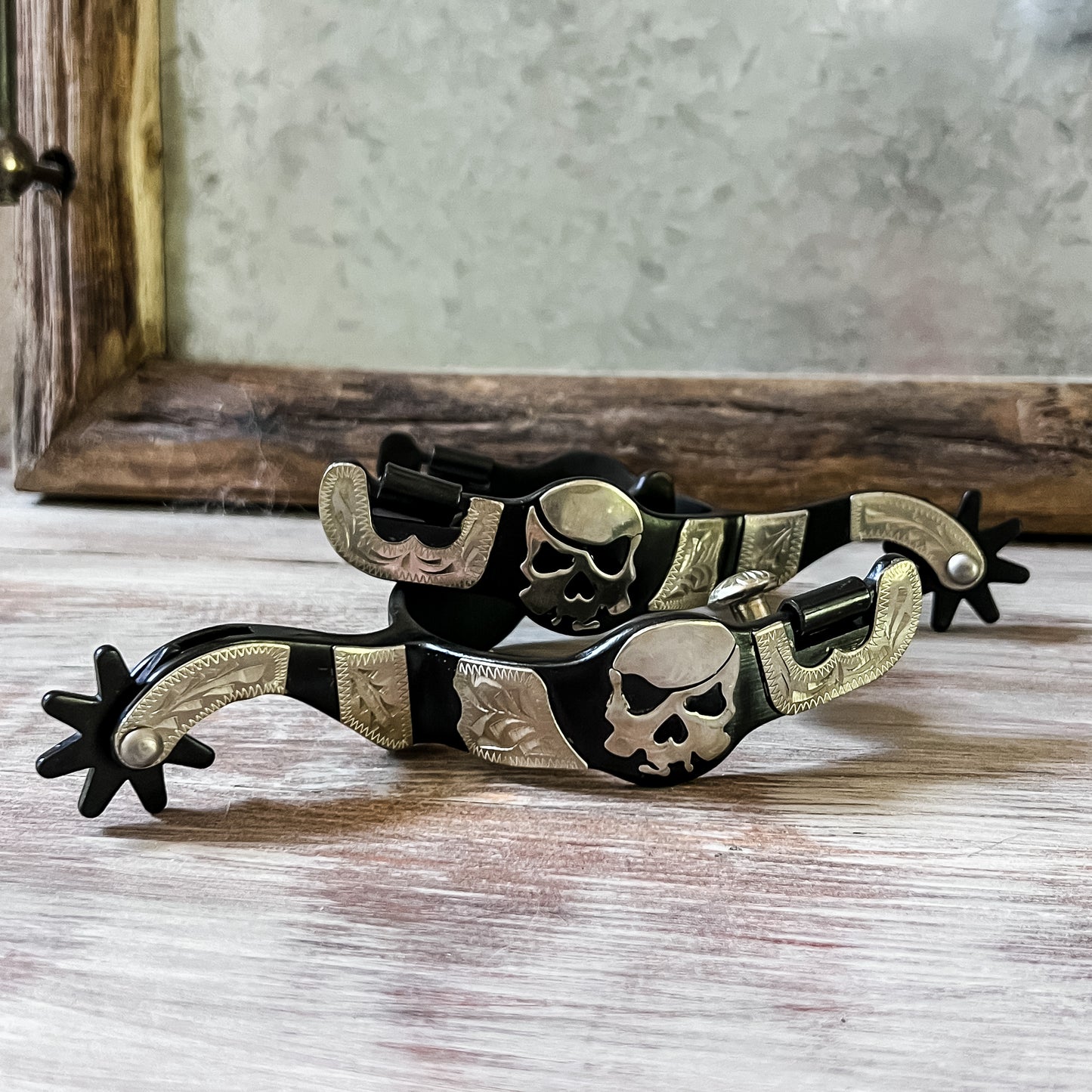 black steel west style show spurs with pirate skull motif and hand engraved silver overlay