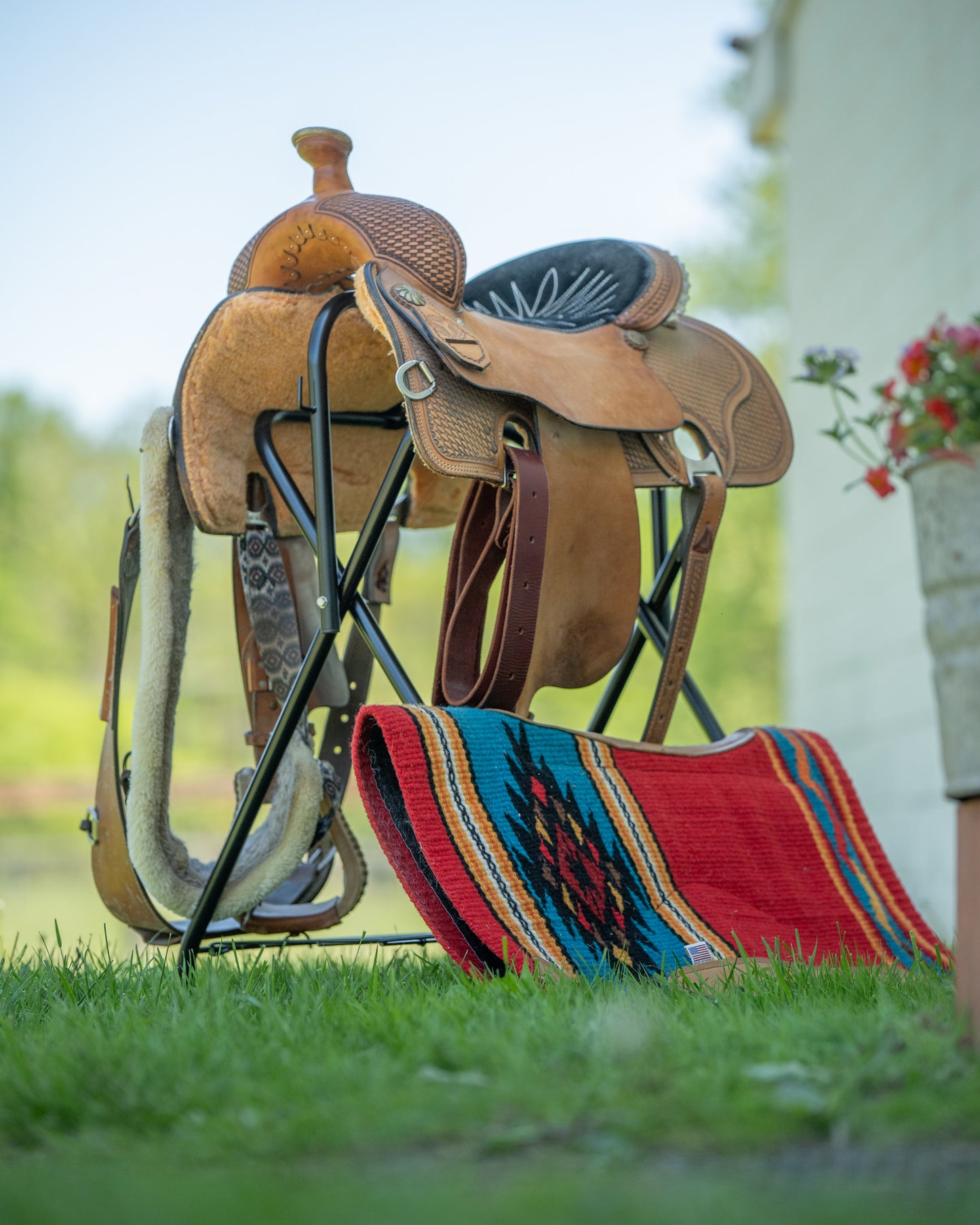 Saddle on a stand with a colorful rug on grass