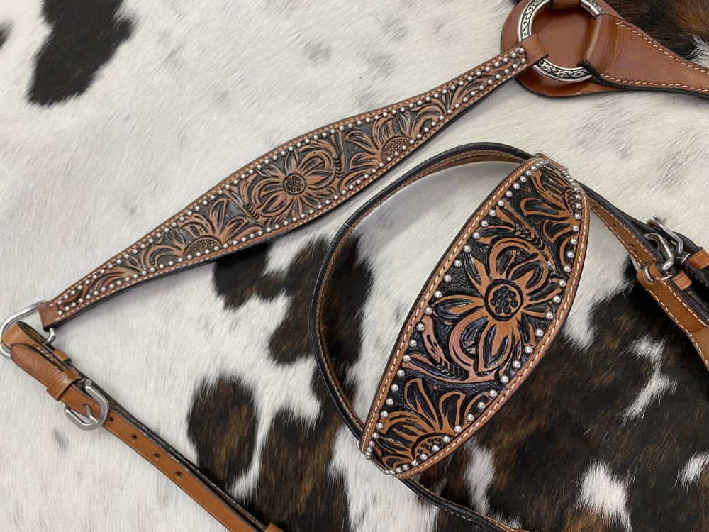 Leather headstall and breast collar with floral tooling on a cowhide rug